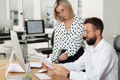 Photo of Technicians making digital engineering drawing on computer at desk in office