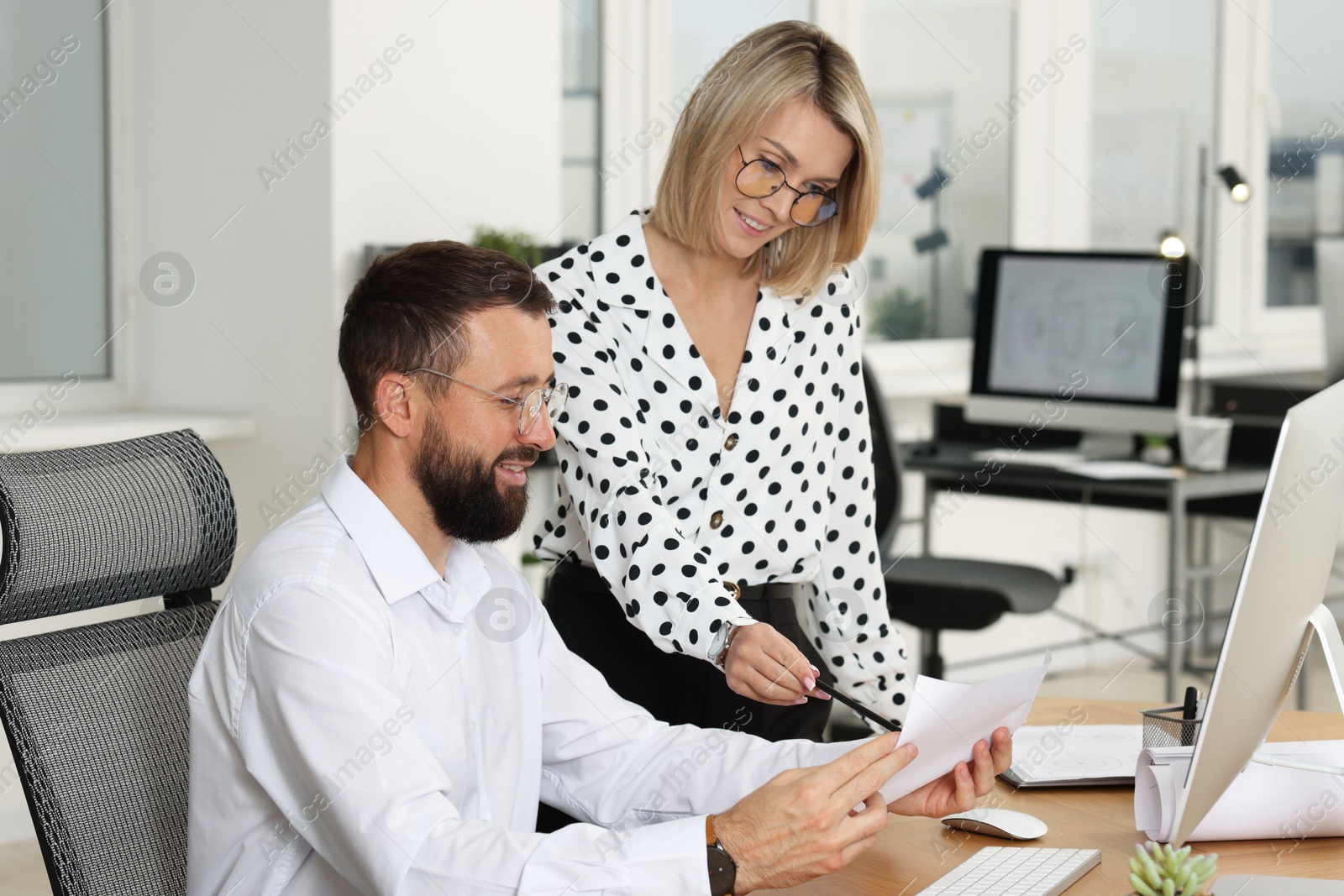 Photo of Technicians making digital engineering drawing on computer at desk in office