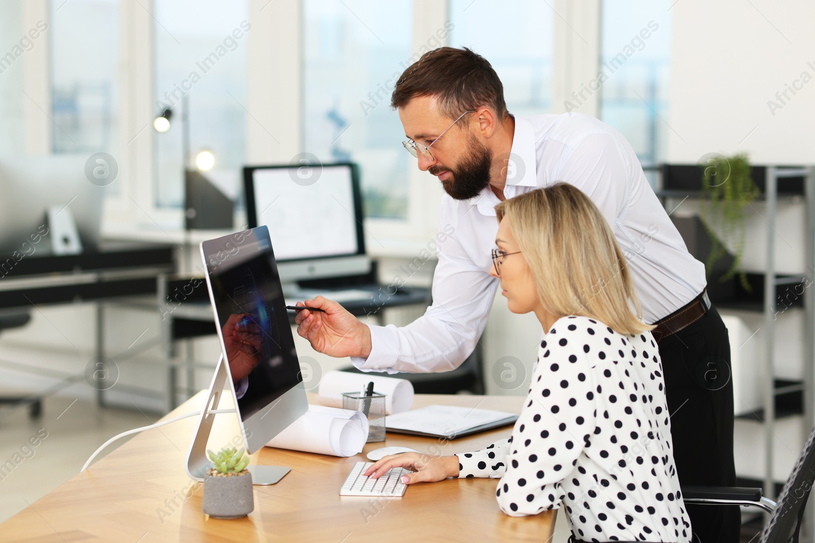 Photo of Technicians making digital engineering drawing on computer at desk in office