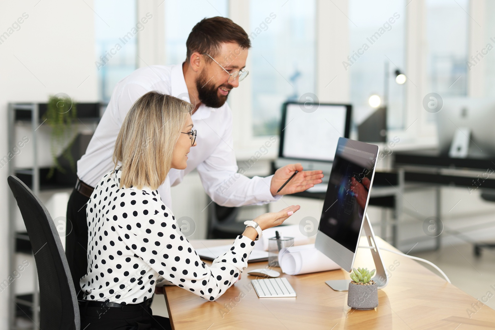 Photo of Technicians making digital engineering drawing on computer at desk in office