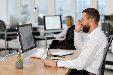 Photo of Technician making digital engineering drawing on computer at desk in office