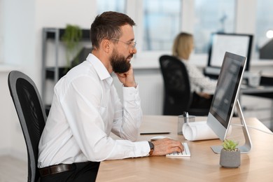 Photo of Technician making digital engineering drawing on computer at desk in office