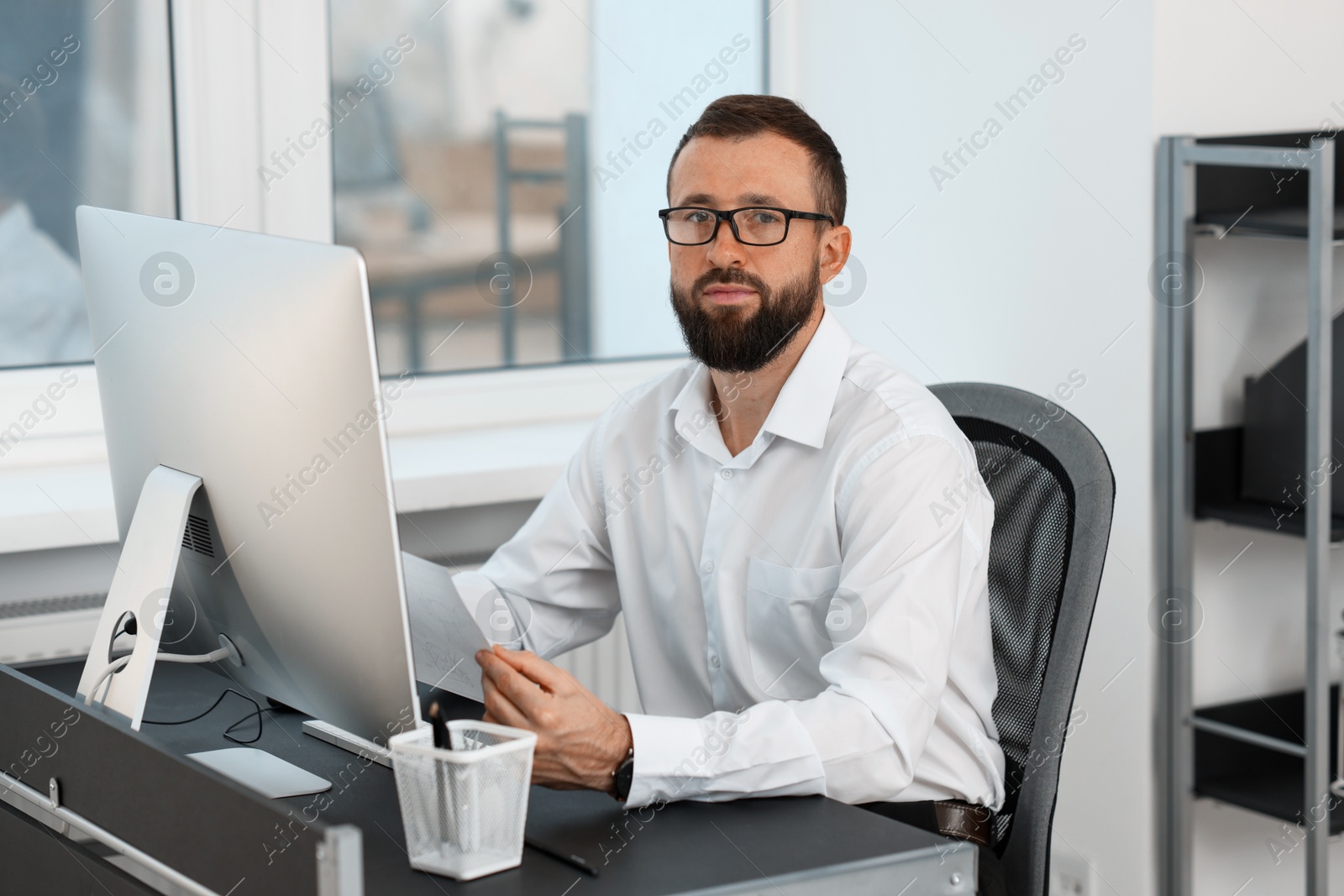 Photo of Technician making digital engineering drawing on computer at desk in office