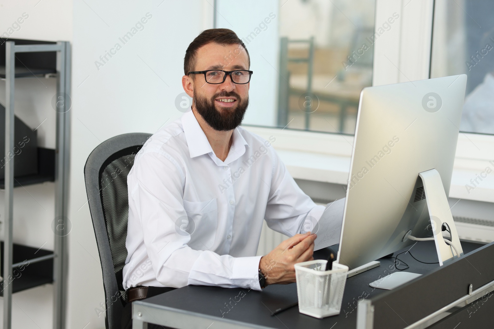 Photo of Technician making digital engineering drawing on computer at desk in office