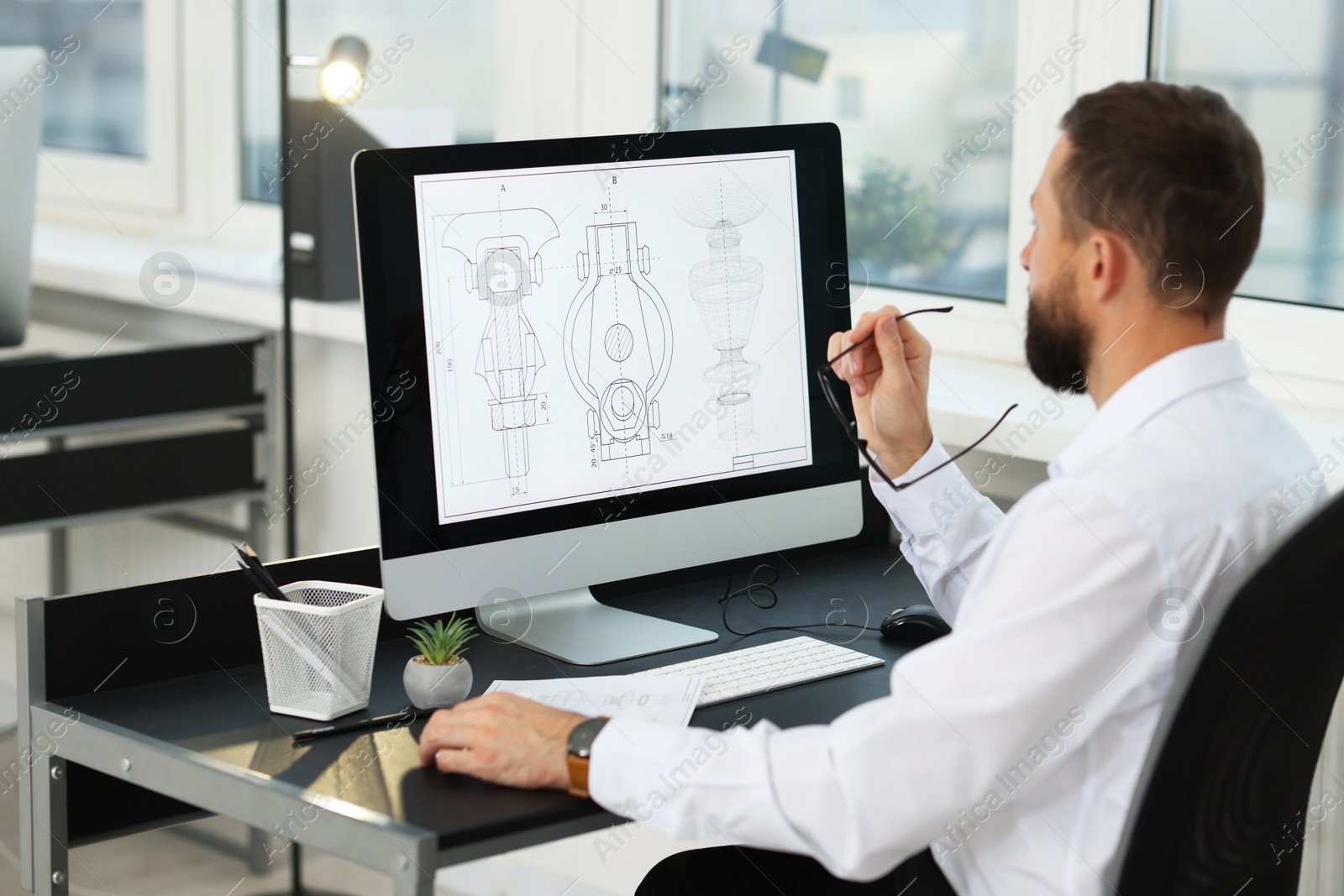 Photo of Technician making digital engineering drawing on computer at desk in office