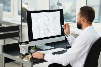 Photo of Technician making digital engineering drawing on computer at desk in office