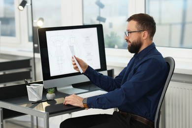 Photo of Technician making digital engineering drawing on computer at desk in office