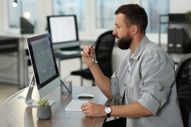 Photo of Technician making digital engineering drawing on computer at desk in office