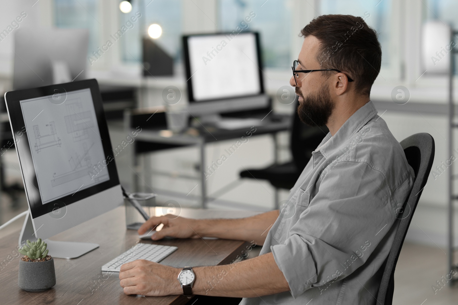 Photo of Technician making digital engineering drawing on computer at desk in office