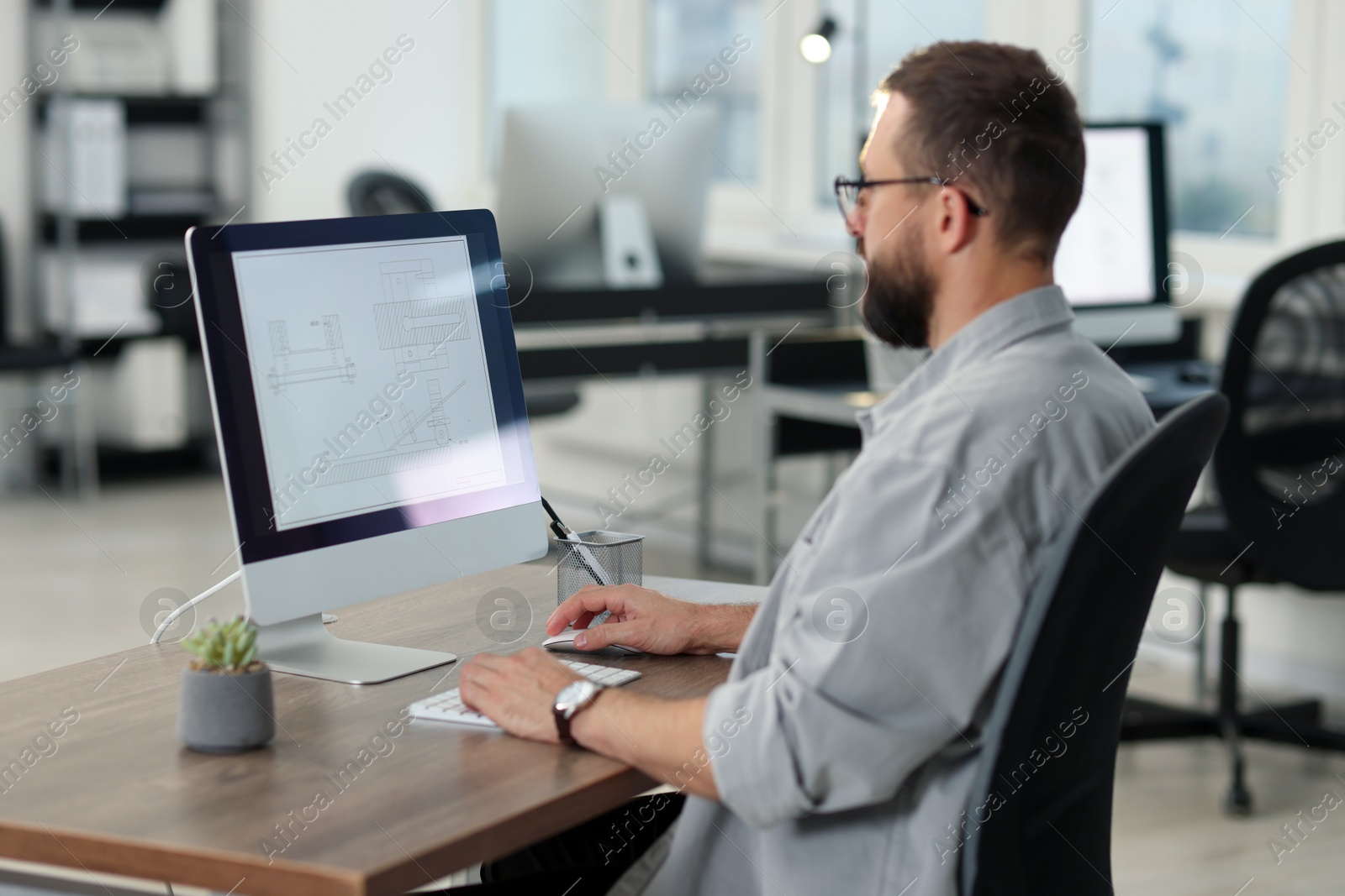 Photo of Technician making digital engineering drawing on computer at desk in office