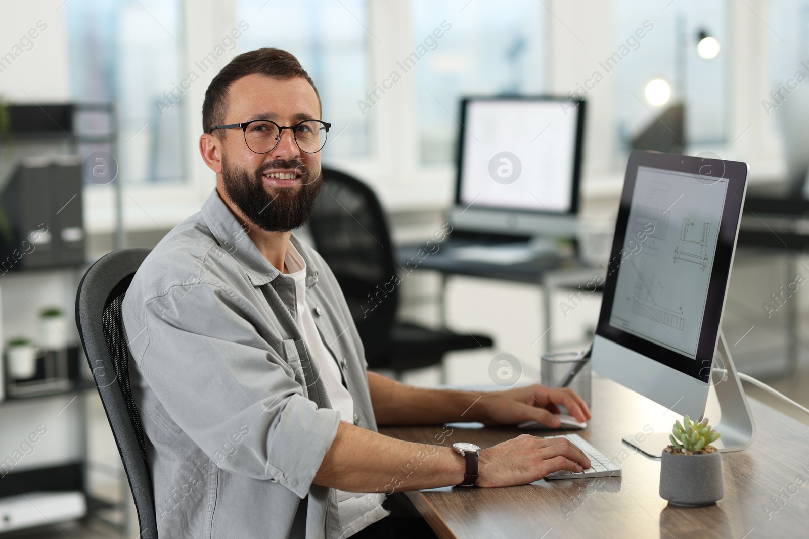 Photo of Technician making digital engineering drawing on computer at desk in office