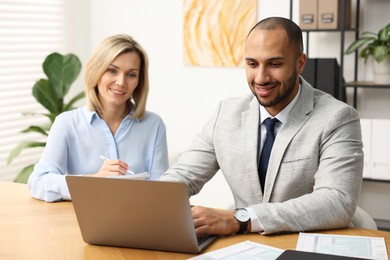 Photo of Coworkers with laptop working together in office