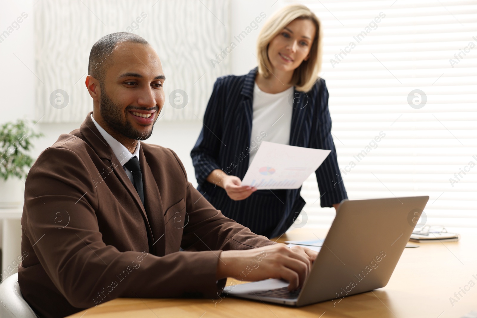 Photo of Coworkers with laptop working together in office