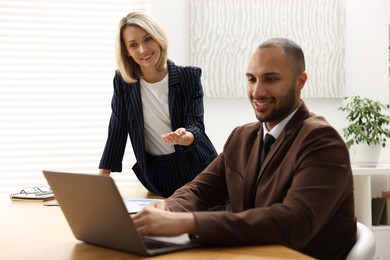 Photo of Coworkers with laptop working together in office