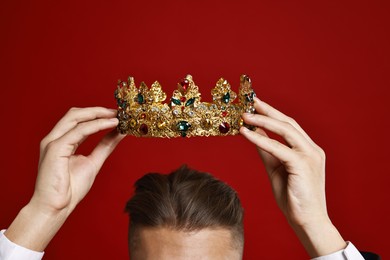 Photo of Man wearing luxury crown on red background, closeup