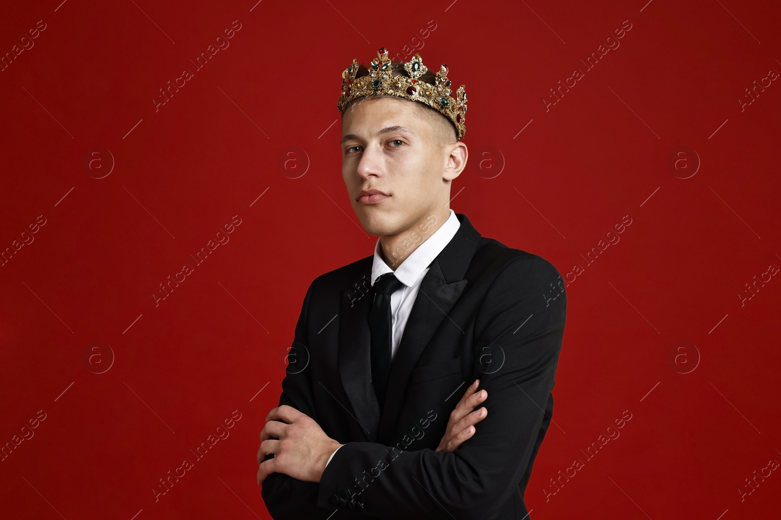 Photo of Handsome man wearing luxury crown on red background