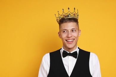 Photo of Handsome man wearing luxury crown on orange background, space for text