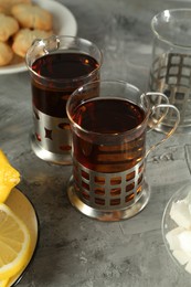 Glasses of tea in metal holders served on grey textured table, closeup