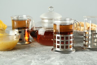 Glasses of tea in metal holders served on grey textured table, closeup