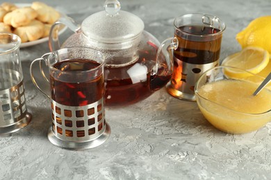 Glasses of tea in metal holders served on grey textured table, closeup