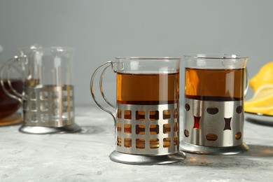 Glasses of tea in metal holders served on grey textured table, closeup