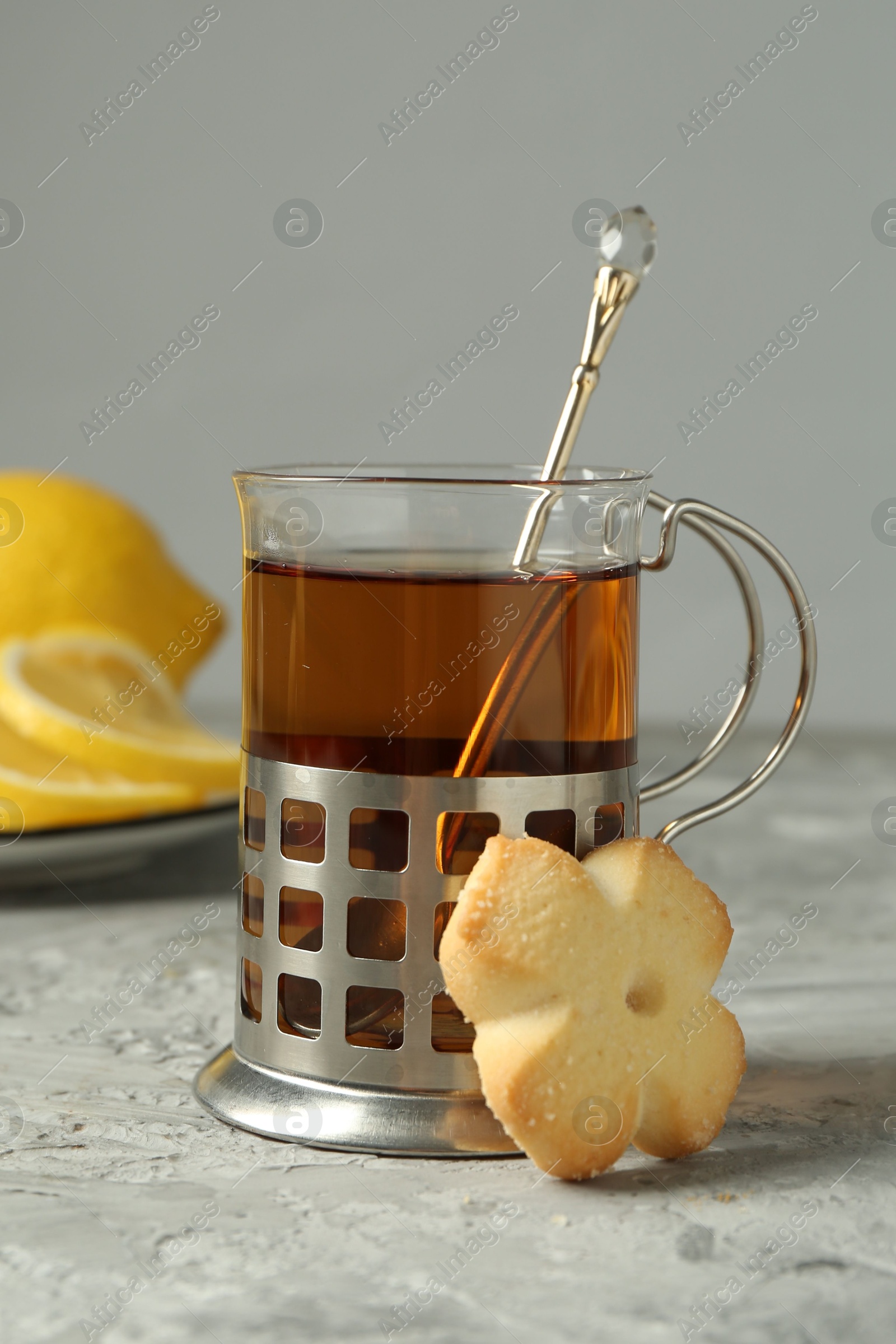 Photo of Glass of tea in metal holder served on grey textured table, closeup