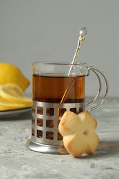 Glass of tea in metal holder served on grey textured table, closeup