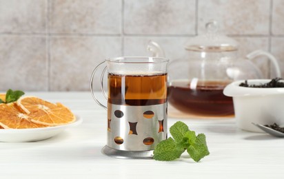 Glass of tea in metal holder served on white wooden table