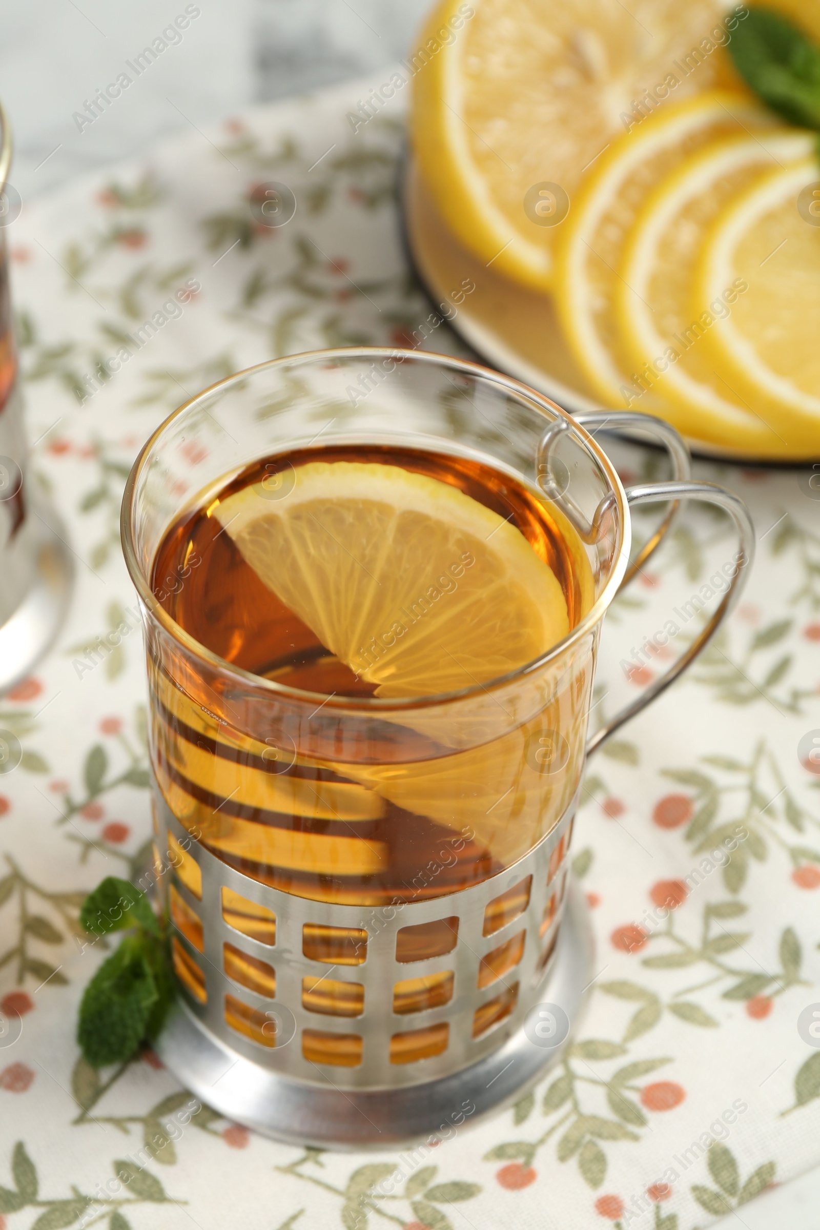 Photo of Glass of tea in metal holder served on table, closeup