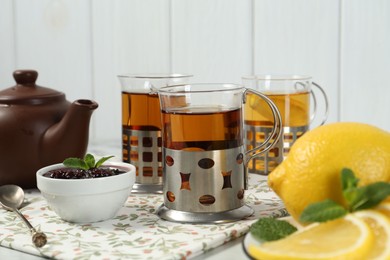 Glasses of tea in metal holders served on white table, closeup