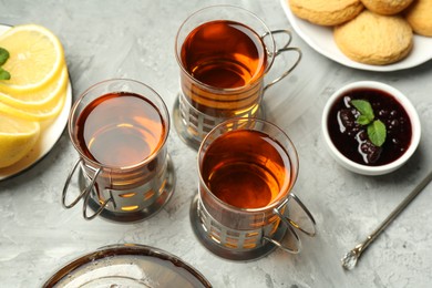 Glasses of tea in metal holders served on grey textured table, above view