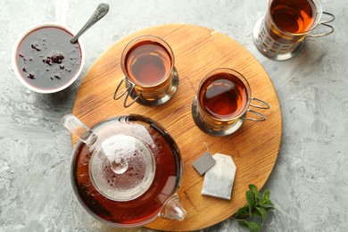 Photo of Glasses of tea in metal holders served on grey textured table, flat lay