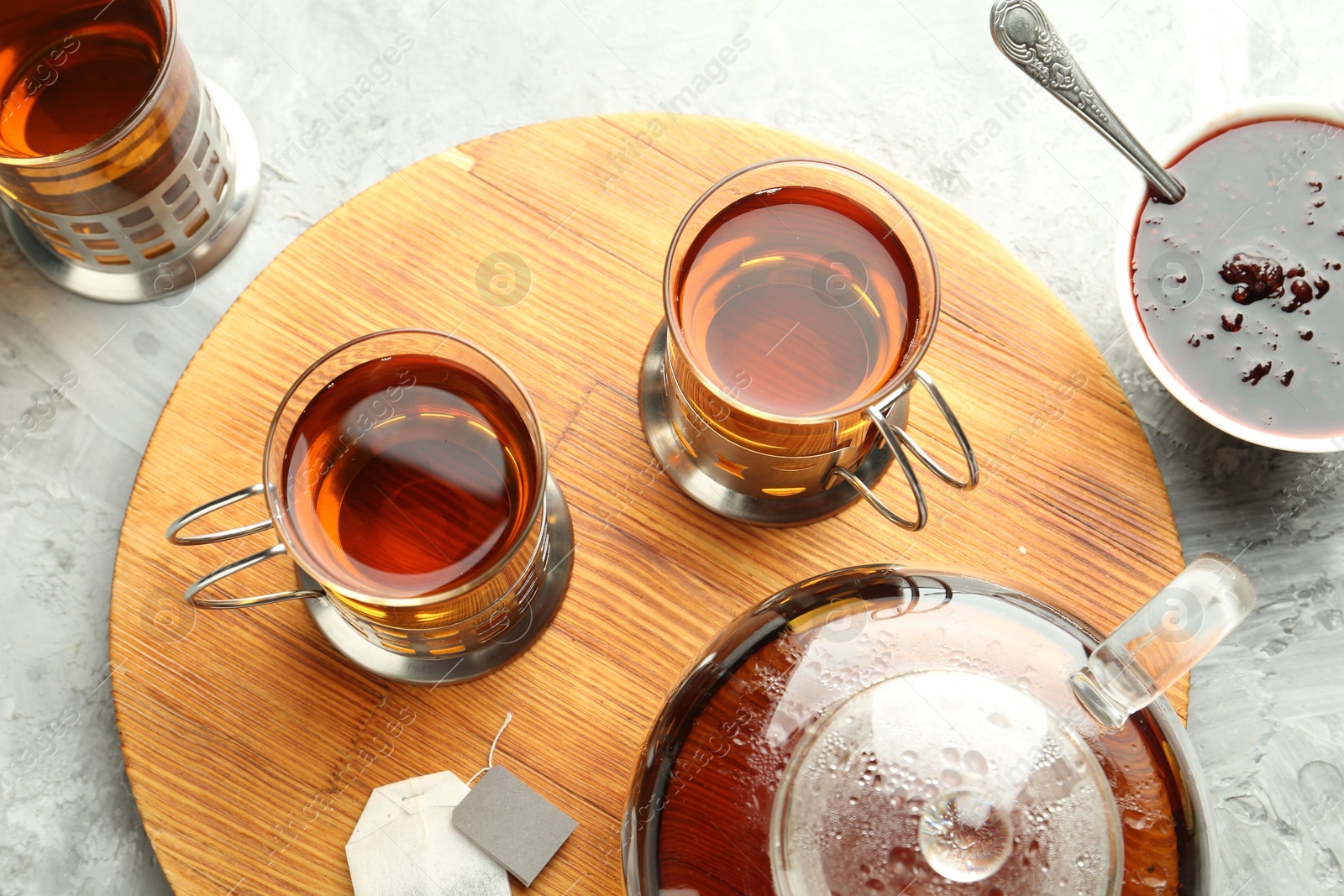 Photo of Glasses of tea in metal holders served on grey textured table, flat lay