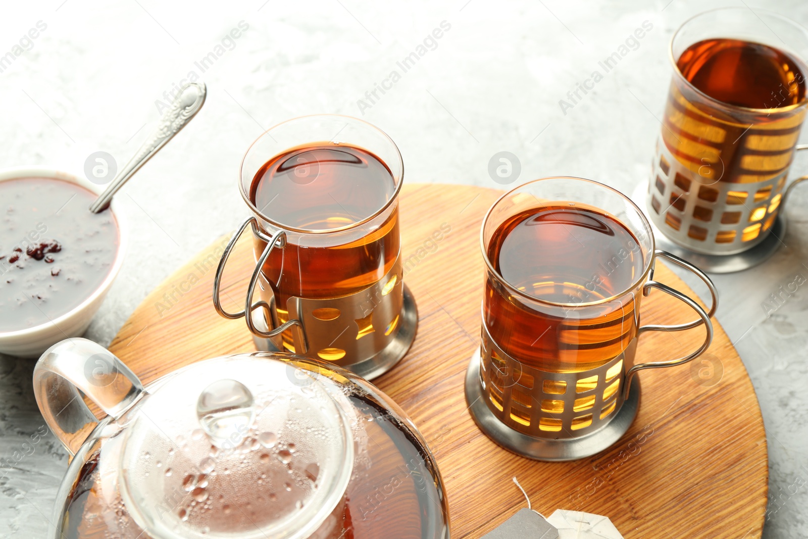 Photo of Glasses of tea in metal holders served on grey textured table, closeup