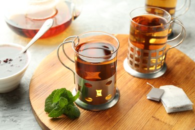 Photo of Glasses of tea in metal holders served on grey textured table, closeup