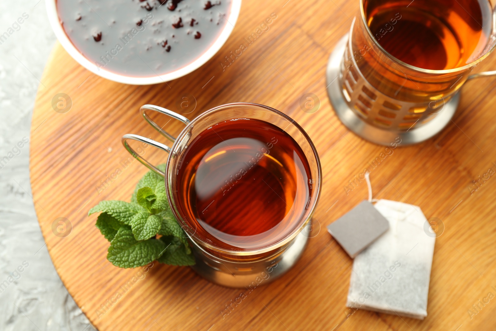 Photo of Glasses of tea in metal holders served on grey textured table, flat lay