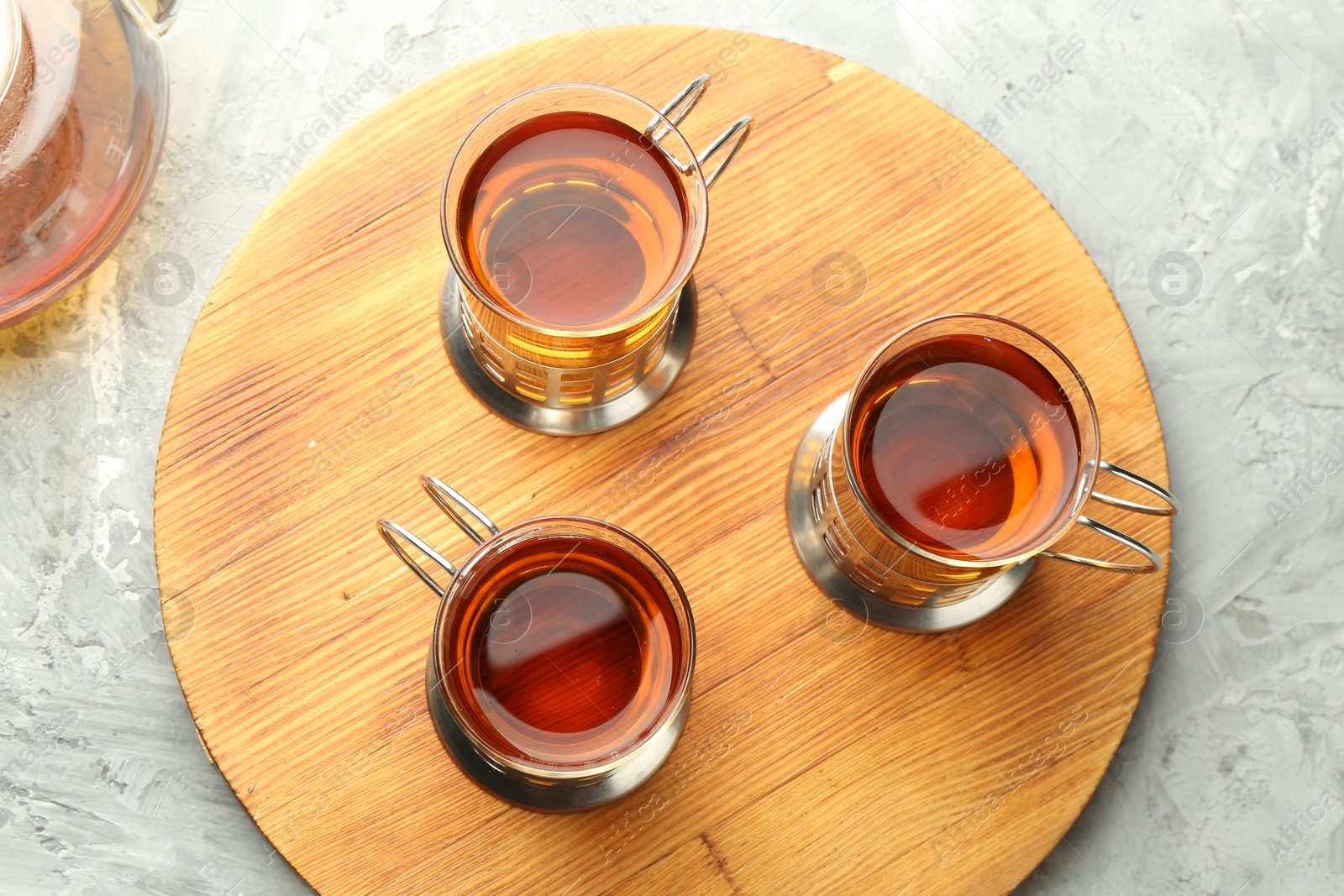 Photo of Glasses of tea in metal holders served on grey textured table, flat lay