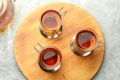 Photo of Glasses of tea in metal holders served on grey textured table, flat lay