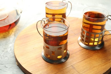 Photo of Glasses of tea in metal holders served on grey textured table, closeup