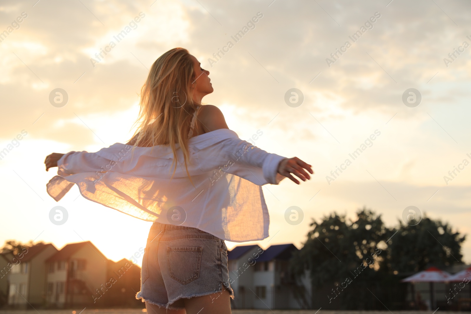 Photo of Young woman with beautiful blond hair outdoors at sunset