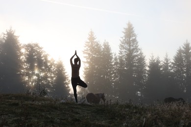 Photo of Woman practicing yoga in mountains at sunrise, back view