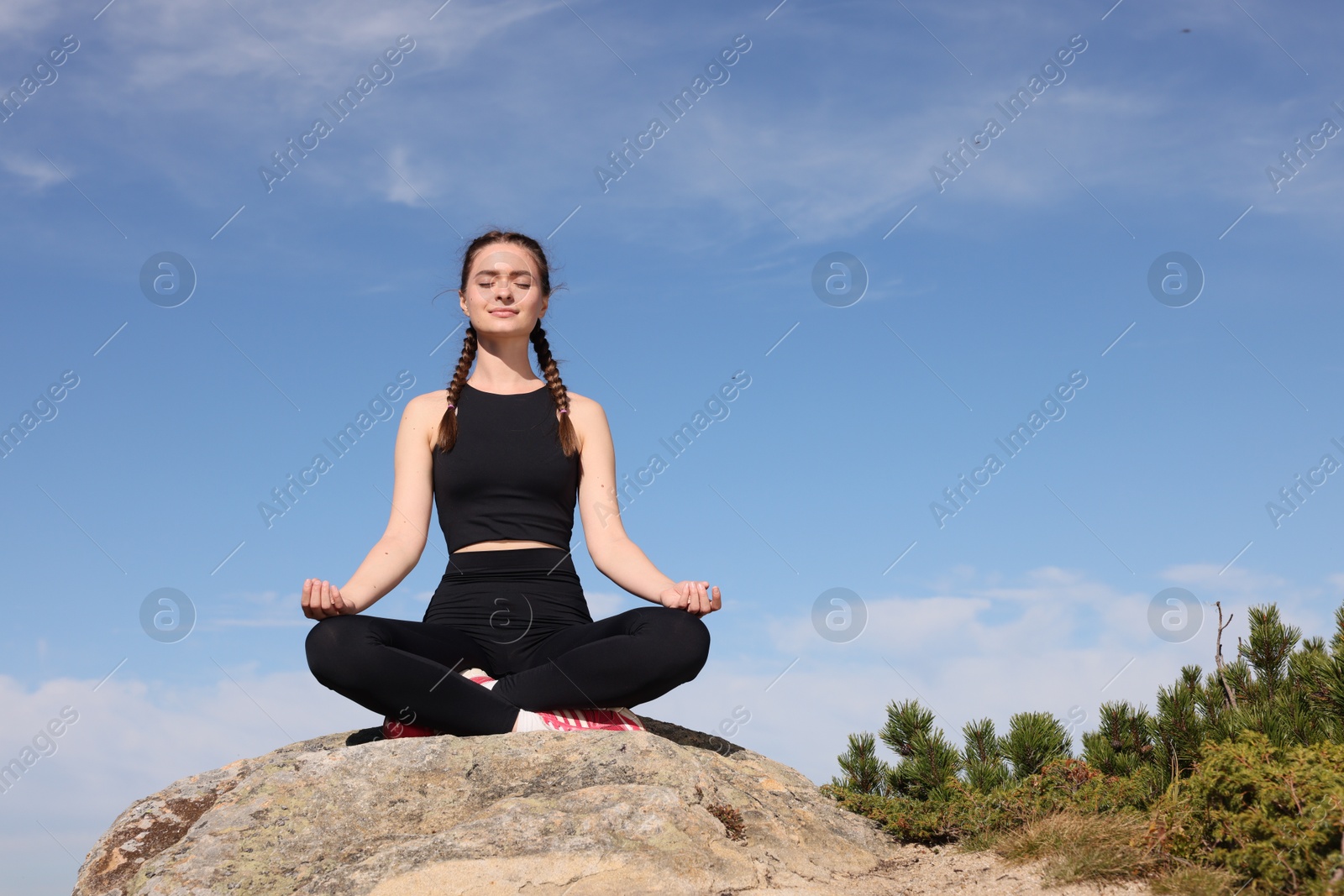 Photo of Young woman practicing outdoor yoga in mountains, space for text. Fitness lifestyle