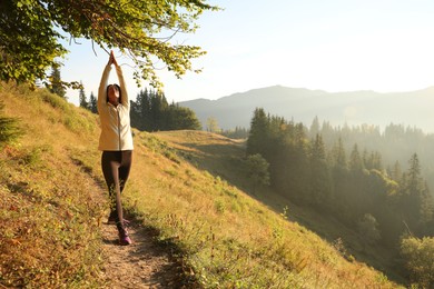 Photo of Woman practicing yoga in mountains at sunrise