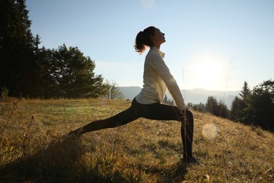 Photo of Woman practicing yoga in mountains at sunrise