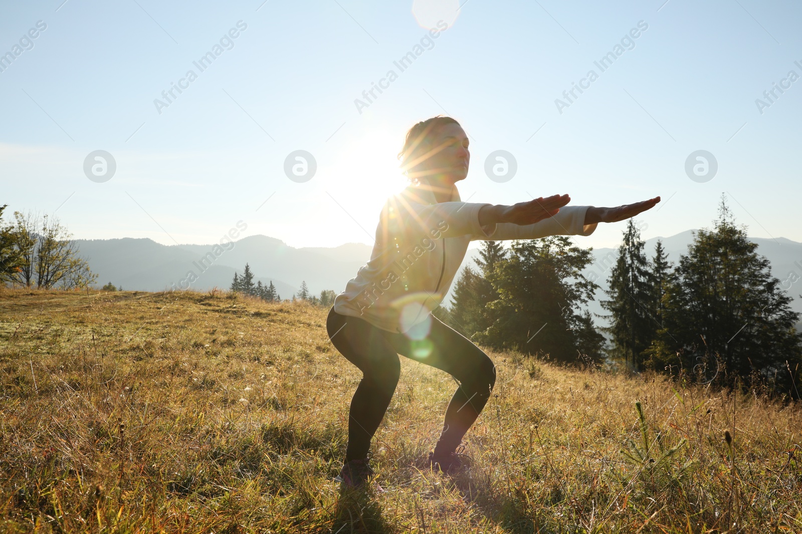 Photo of Woman practicing yoga in mountains at sunrise