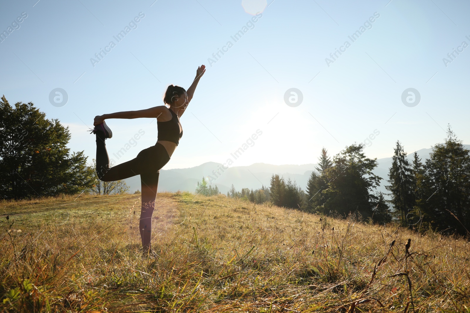 Photo of Woman practicing yoga in mountains at sunrise