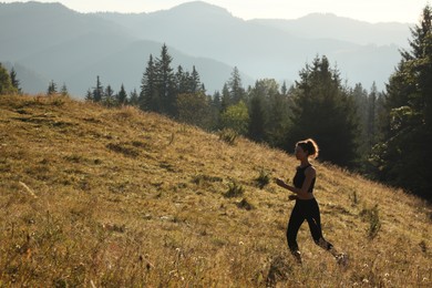 Photo of Sporty woman running on grassy hill in mountains