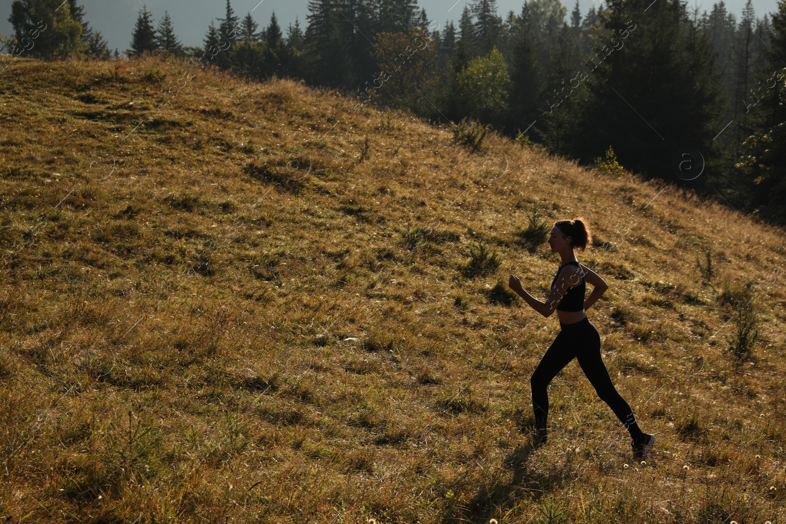 Photo of Sporty woman running on grassy hill in mountains