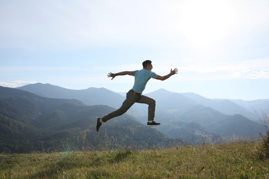 Photo of Sporty man running on grassy hill in mountains