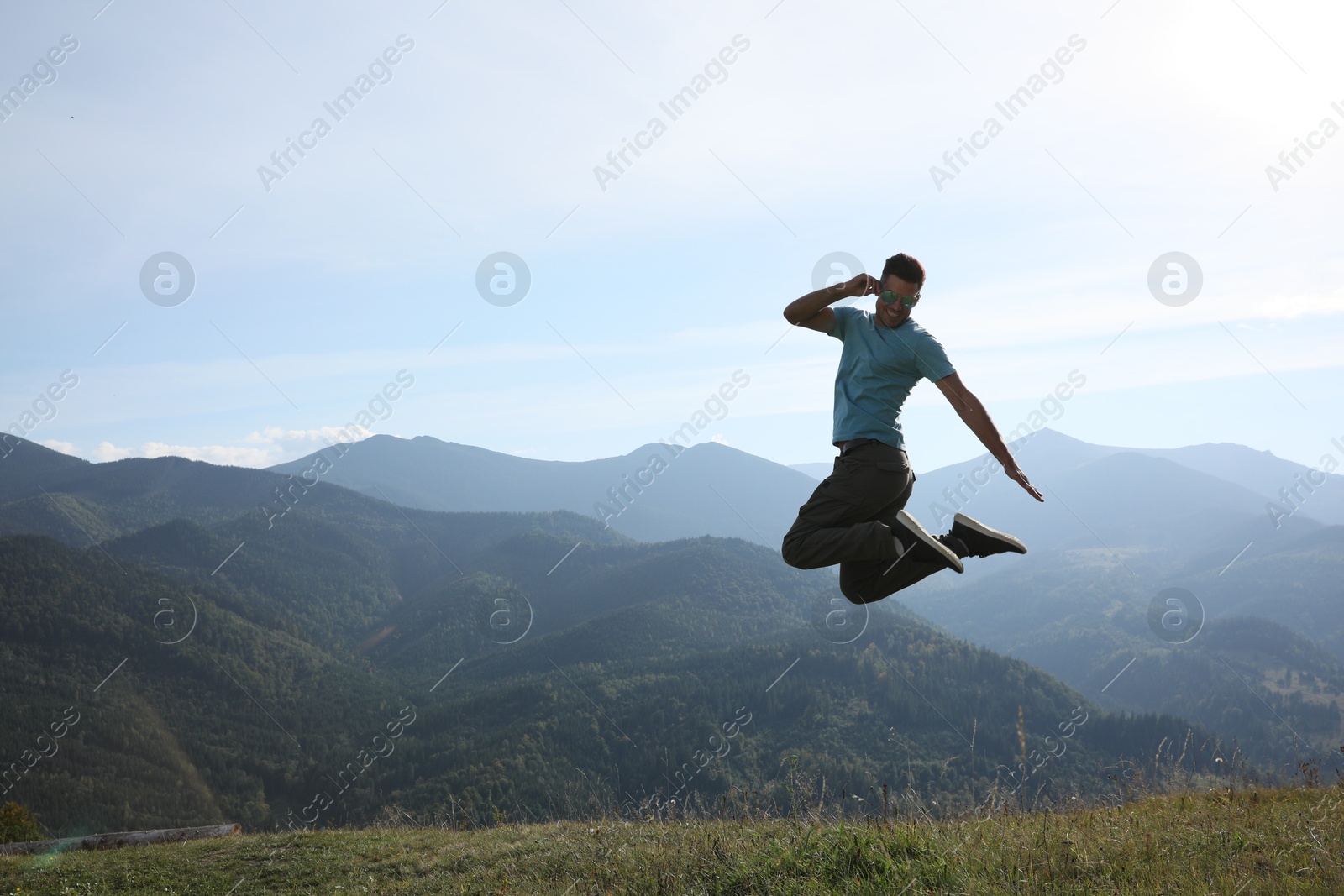 Photo of Sporty man jumping on grassy hill in mountains